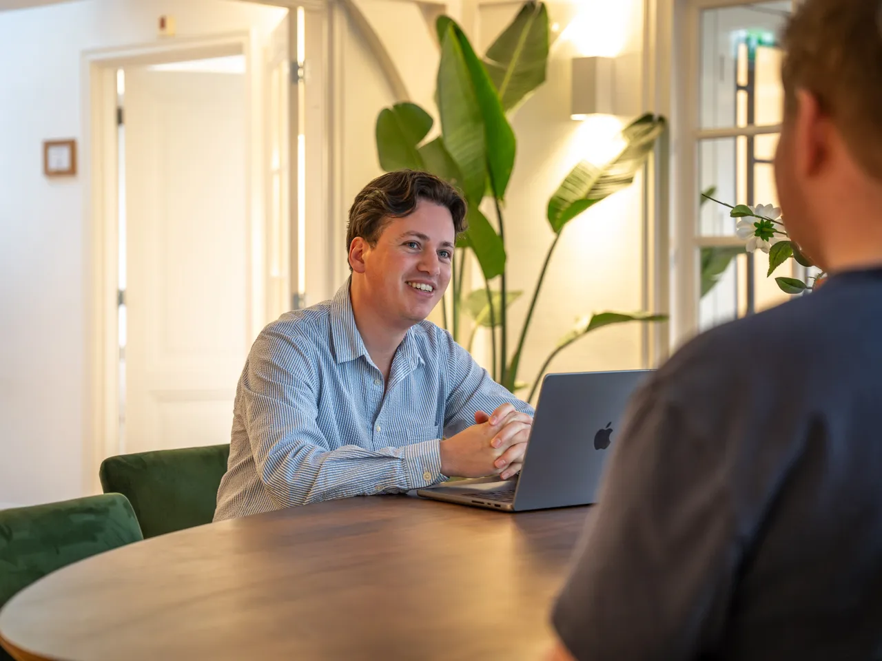 Teamlid van Copilot Cursus in gesprek aan tafel met een laptop